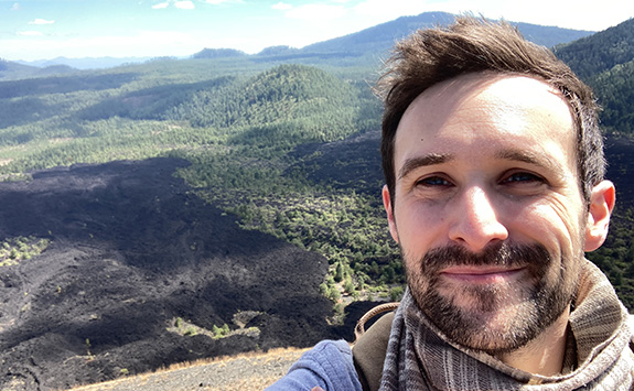 Selfie of Antoine Dorison with mountainous landscape in the backgroun